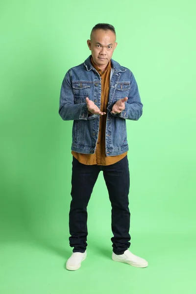 緑の背景にジーンシャツを着た40代のアジア系成人男性 — ストック写真