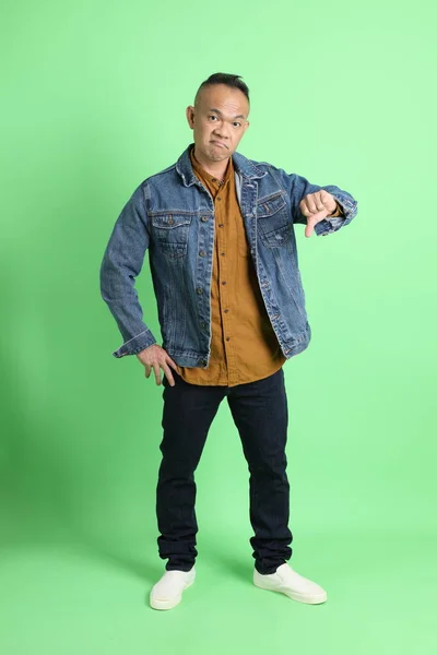 緑の背景にジーンシャツを着た40代のアジア系成人男性 — ストック写真