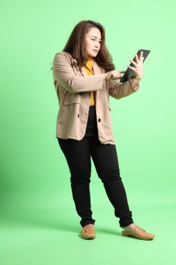 Yeşil arka planda duran Asyalı yetişkin iş kadını..