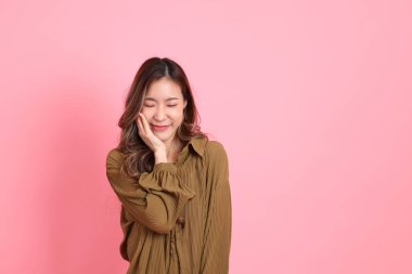 The young adult Asian woman with brown dressed standing on the pink background.