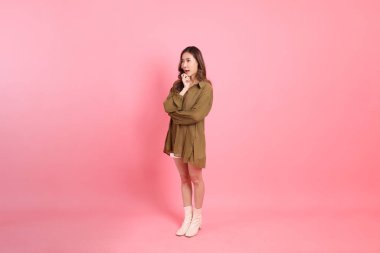 The young adult Asian woman with brown dressed standing on the pink background.
