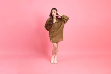 The young adult Asian woman with brown dressed standing on the pink background.