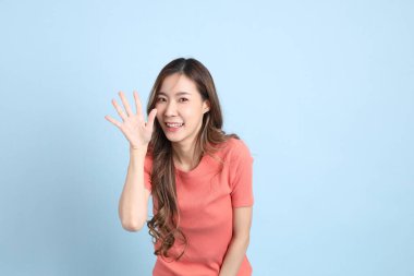 The young adult Asian woman with casual clothes with jeans standing on the blue background.