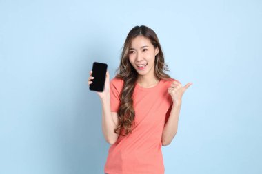 The young adult Asian woman with casual clothes with jeans standing on the blue background.