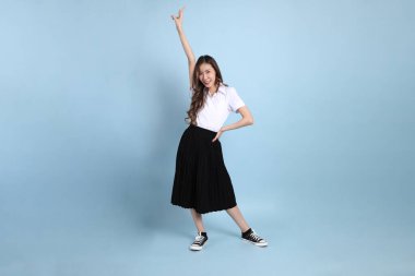The young Asian student with uniform standing on the blue background.