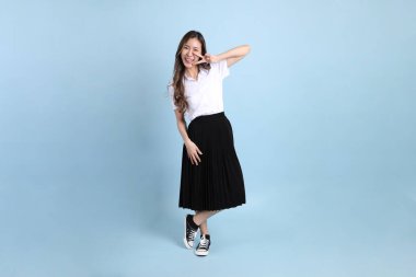 The young Asian student with uniform standing on the blue background.