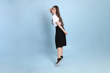 The young Asian student with uniform standing on the blue background.