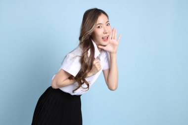 The young Asian student with uniform standing on the blue background.