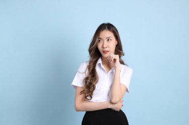 The young Asian student with uniform standing on the blue background.