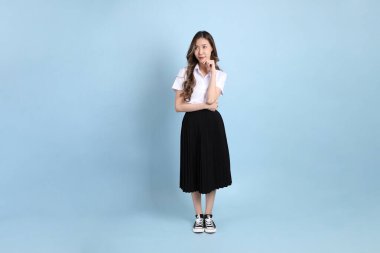The young Asian student with uniform standing on the blue background.