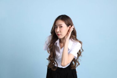 The young Asian student with uniform standing on the blue background.