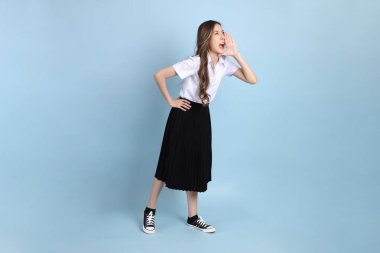 The young Asian student with uniform standing on the blue background.
