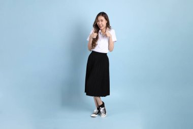 The young Asian student with uniform standing on the blue background.