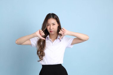 The young Asian student with uniform standing on the blue background.