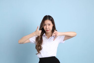 The young Asian student with uniform standing on the blue background.