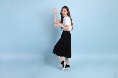 The young Asian student with uniform standing on the blue background.