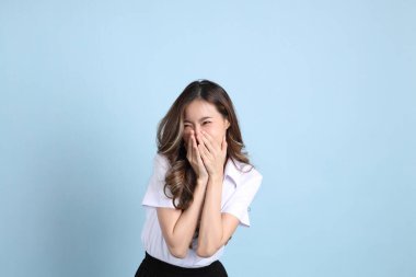 The young Asian student with uniform standing on the blue background.