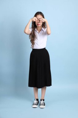 The young Asian student with uniform standing on the blue background.