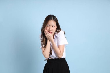 The young Asian student with uniform standing on the blue background.