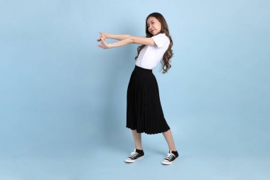 The young Asian student with uniform standing on the blue background.
