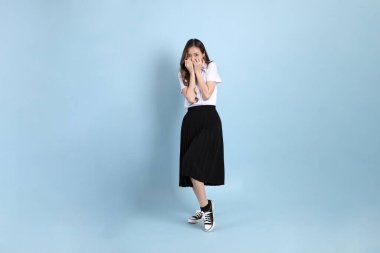 The young Asian student with uniform standing on the blue background.