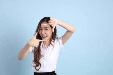 The young Asian student with uniform standing on the blue background.