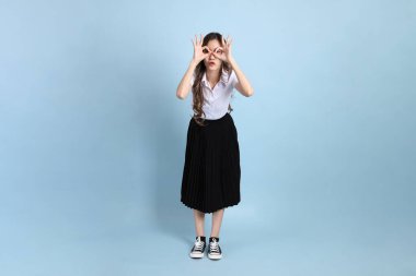 The young Asian student with uniform standing on the blue background.
