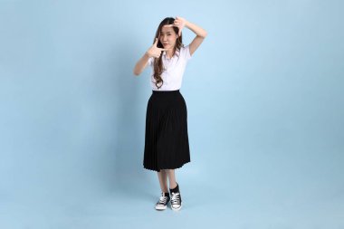 The young Asian student with uniform standing on the blue background.