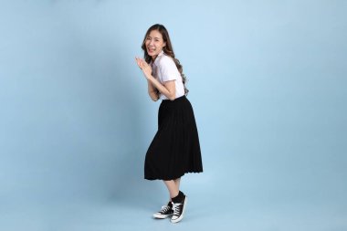 The young Asian student with uniform standing on the blue background.