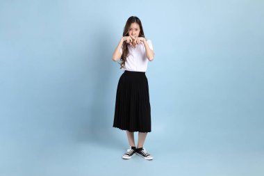 The young Asian student with uniform standing on the blue background.