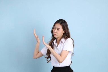 The young Asian student with uniform standing on the blue background.