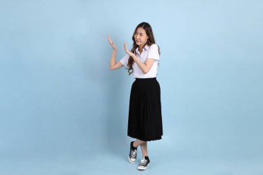 The young Asian student with uniform standing on the blue background.