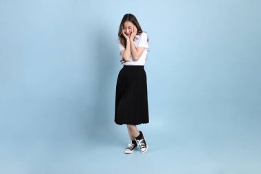 The young Asian student with uniform standing on the blue background.