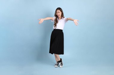 The young Asian student with uniform standing on the blue background.