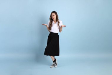 The young Asian student with uniform standing on the blue background.