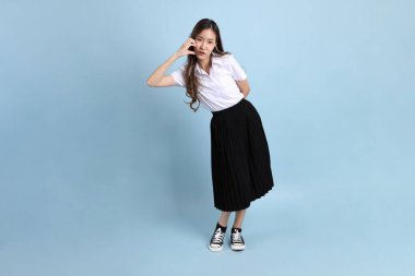 The young Asian student with uniform standing on the blue background.