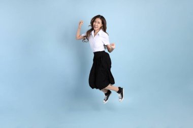 The young Asian student with uniform standing on the blue background.