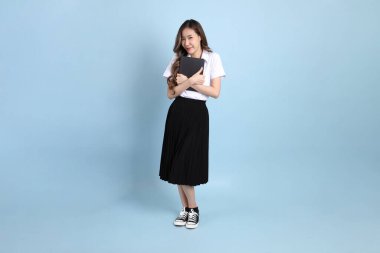The young Asian student with uniform standing on the blue background.