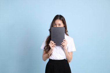 The young Asian student with uniform standing on the blue background.