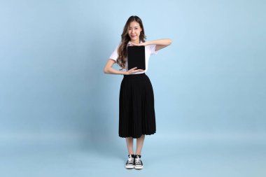 The young Asian student with uniform standing on the blue background.