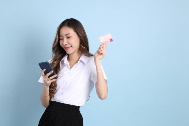 The young Asian student with uniform standing on the blue background.