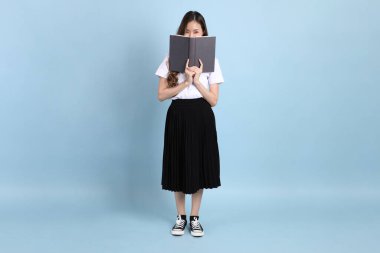 The young Asian student with uniform standing on the blue background.