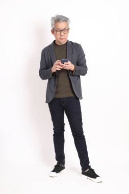 The senior Asian man with grey hair standing on the white background.