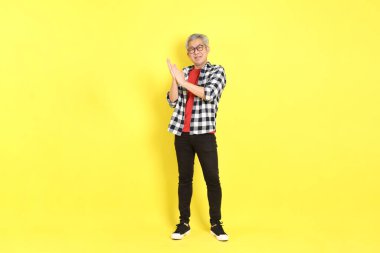The 40s adult Asian man with casual dressed standing on the yellow background.