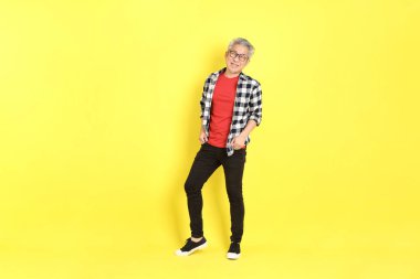 The 40s adult Asian man with casual dressed standing on the yellow background.