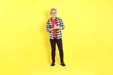The 40s adult Asian man with casual dressed standing on the yellow background.