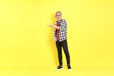 The 40s adult Asian man with casual dressed standing on the yellow background.