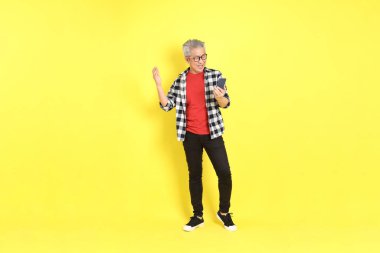 The 40s adult Asian man with casual dressed standing on the yellow background.