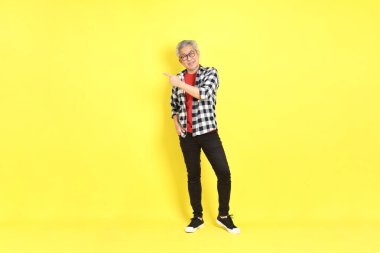 The 40s adult Asian man with casual dressed standing on the yellow background.