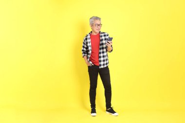 The 40s adult Asian man with casual dressed standing on the yellow background.